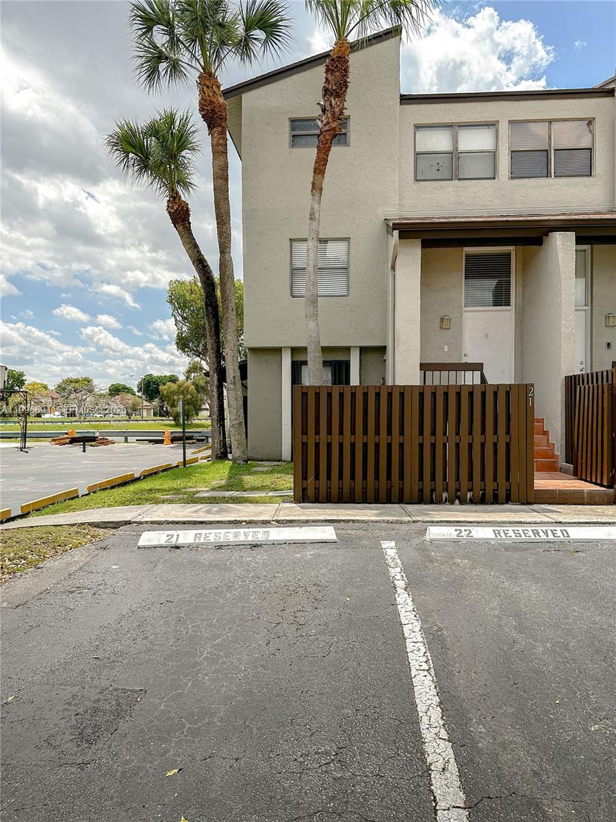 An exterior view of a multi-story townhouse with reserved parking spaces in the foreground — 10000 NW 9th St Cir # 21, Miami FL 33172, MIAMI, FL