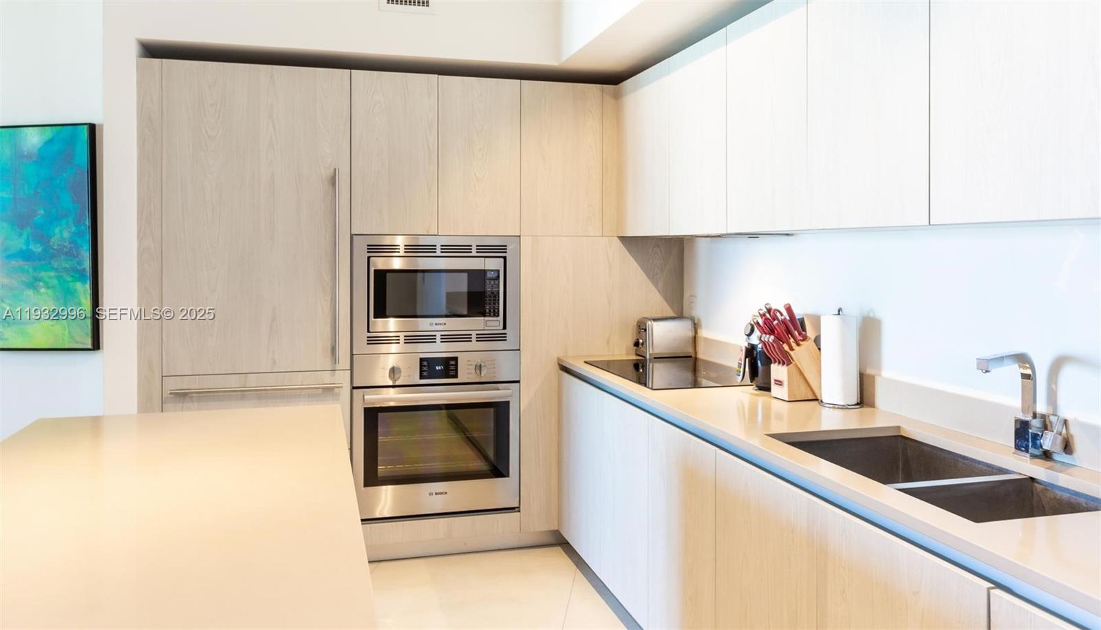 A modern kitchen features light wood cabinetry, stainless steel appliances, and a stone countertop — 4111 S Ocean Dr # 1910, Hollywood FL 33019, HOLLYWOOD, FL