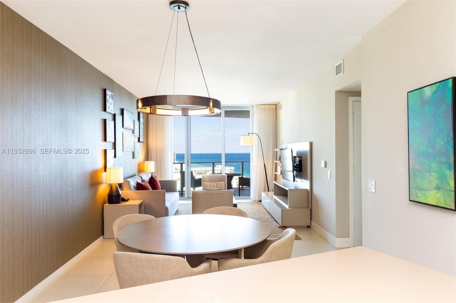 A dining area and living room overlook the ocean through large sliding glass doors — 4111 S Ocean Dr # 1910, Hollywood FL 33019, HOLLYWOOD, FL