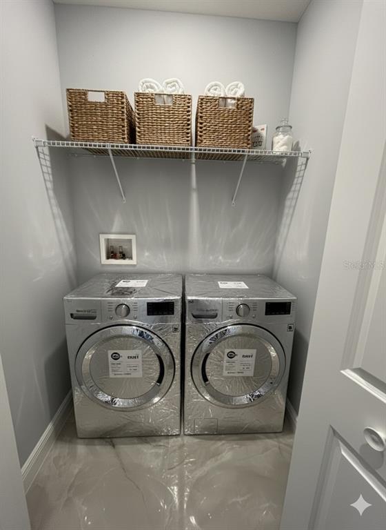 A laundry closet features two silver appliances beneath a wire shelf with woven storage baskets — 373 AMBERJACK COURT, KISSIMMEE, FL