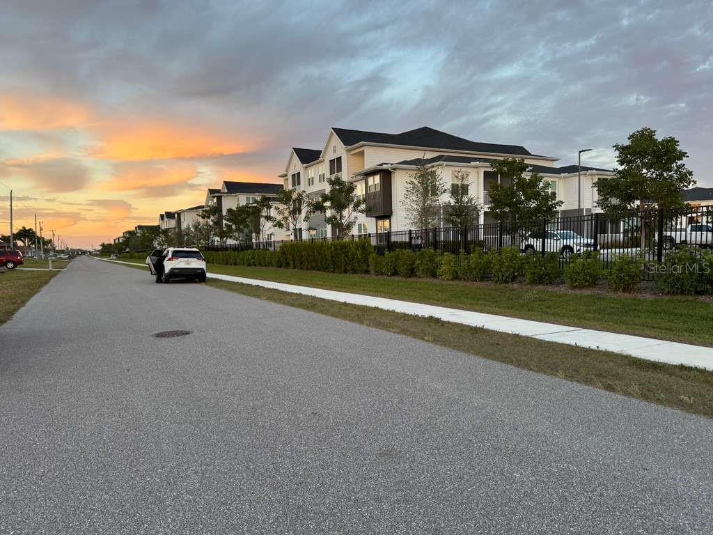 A white multi-story apartment complex sits beside a paved road under a sunset sky — 410 SW 15TH PLACE, CAPE CORAL, FL