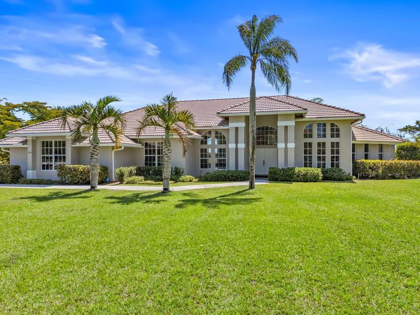 A single-story house with a tiled roof, beige stucco exterior, and palm trees in the yard — 3950 Fieldview Way, Wellington FL 33414, WELLINGTON, FL