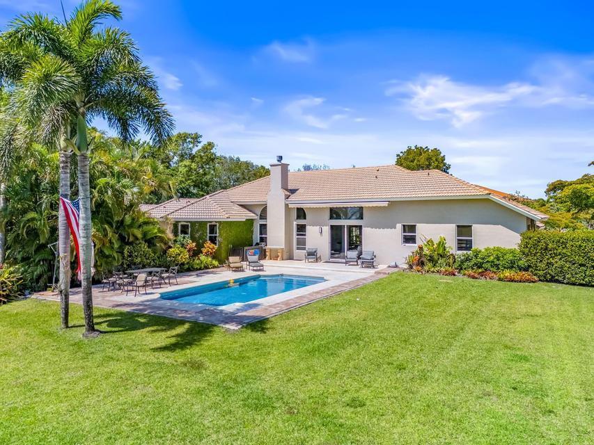 A single-story house with a tiled roof, swimming pool, and patio in a grassy backyard — 3950 Fieldview Way, Wellington FL 33414, WELLINGTON, FL