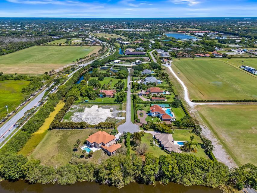 An aerial view shows several houses with swimming pools situated between large grassy fields — 3950 Fieldview Way, Wellington FL 33414, WELLINGTON, FL