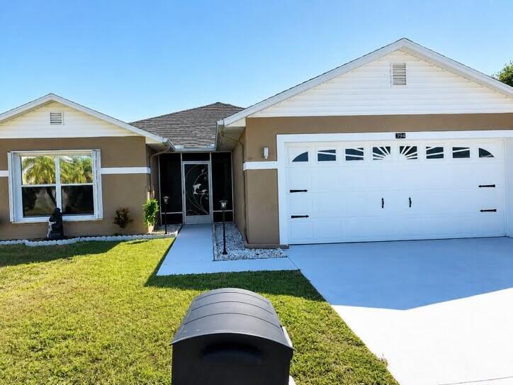 A single-story house with a tan stucco exterior, white trim, and a two-car garage — 6794 Picante Circle, Fort Pierce FL 34951, FORT PIERCE, FL