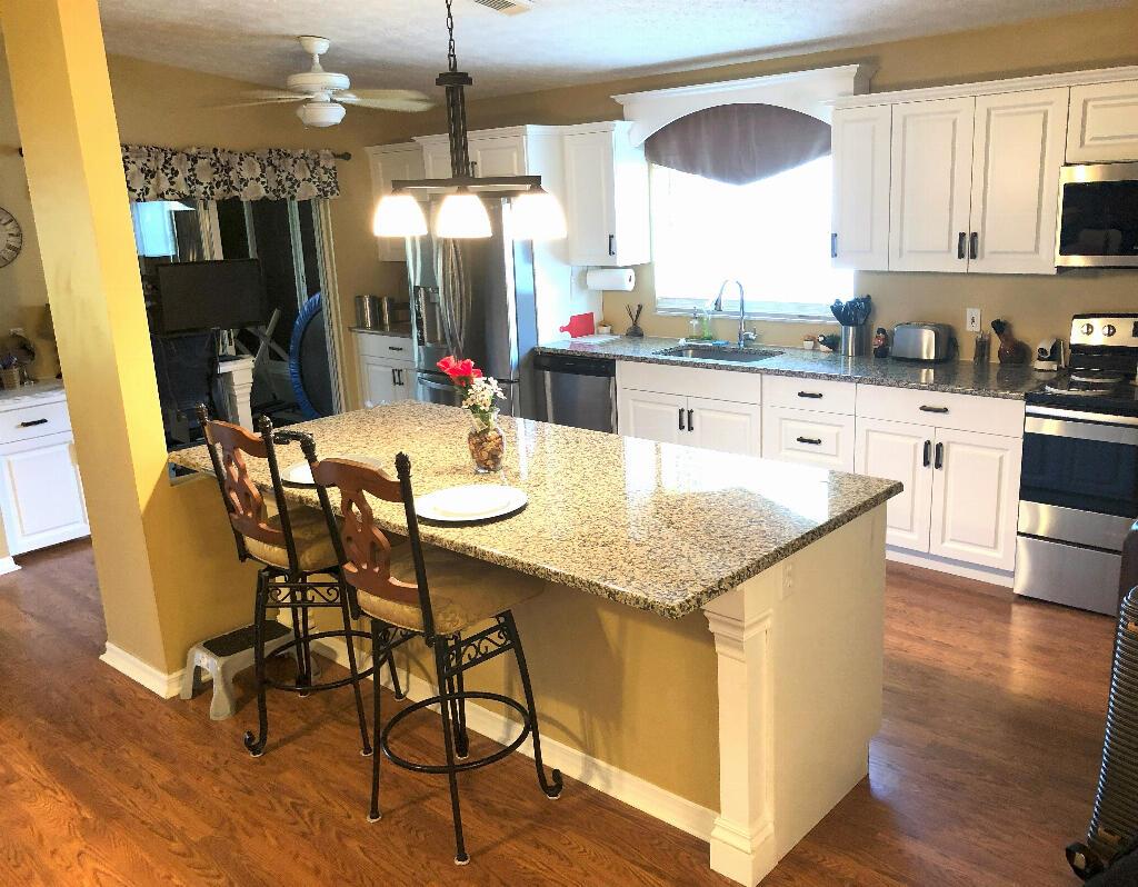 A dining room features a dark wood table, upholstered chairs, a sideboard, and hardwood floors — 6794 Picante Circle, Fort Pierce FL 34951, FORT PIERCE, FL