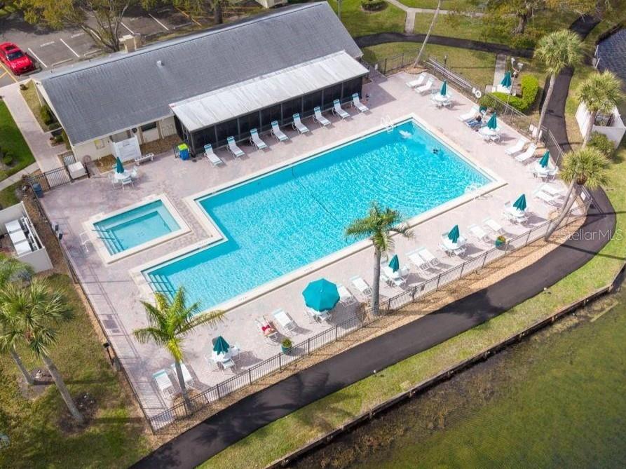 An aerial view shows a rectangular swimming pool and hot tub with lounge chairs nearby — 3101 LAKE PINE WAY UNIT A1, TARPON SPRINGS, FL