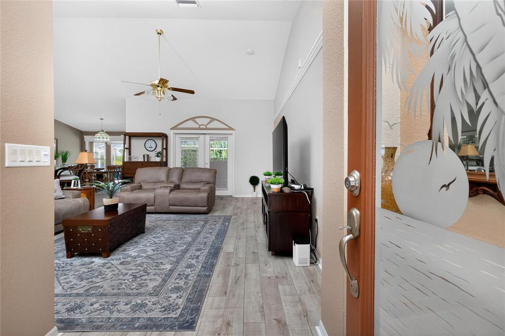 A view from an entryway into a living room with wood-look flooring and a ceiling fan — 1112 MUSCOVIE COURT, PUNTA GORDA, FL