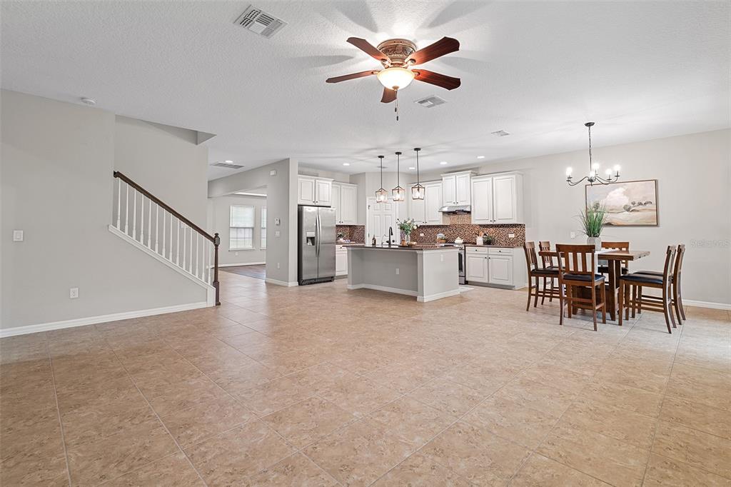 An open-concept kitchen and dining area features tile flooring, white cabinetry, and a center island — 14048 WATERFORD CREEK BOULEVARD, ORLANDO, FL
