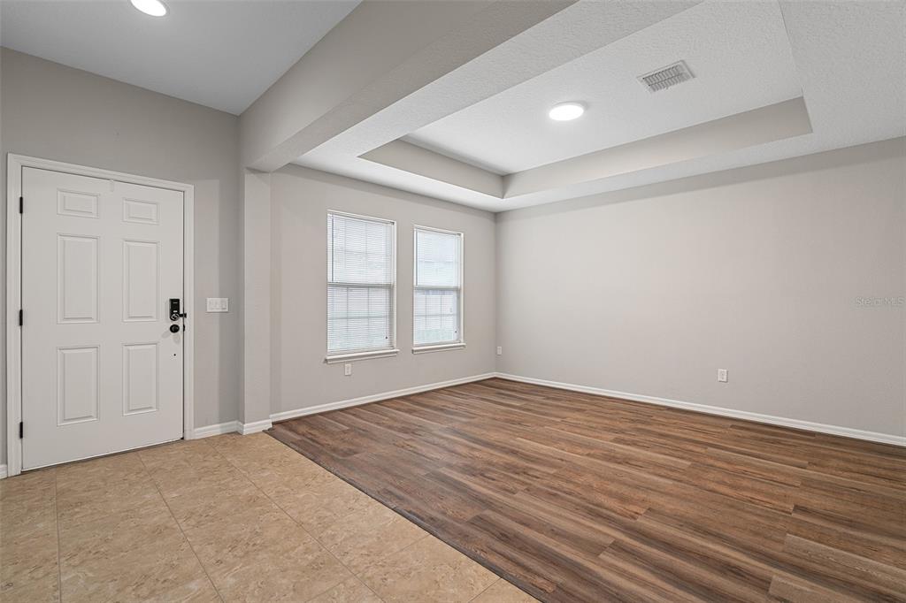 An empty room features a tray ceiling, wood-look flooring, and a tiled entryway — 14048 WATERFORD CREEK BOULEVARD, ORLANDO, FL