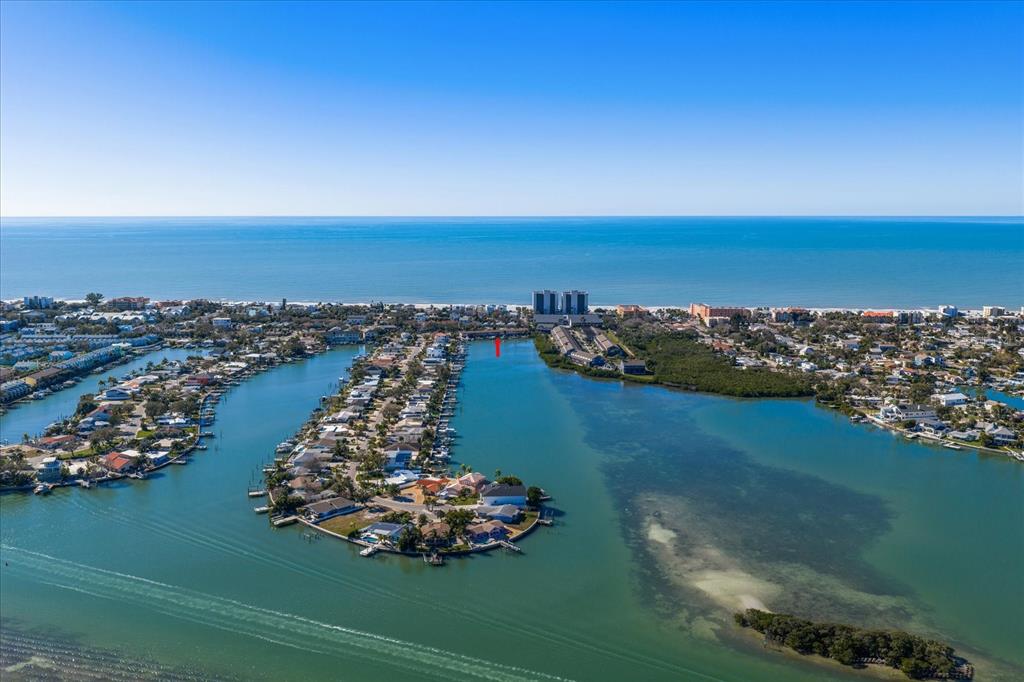An aerial view shows a residential peninsula surrounded by water near a coastal beach — 829 E GULF BOULEVARD UNIT 107, INDIAN ROCKS BEACH, FL