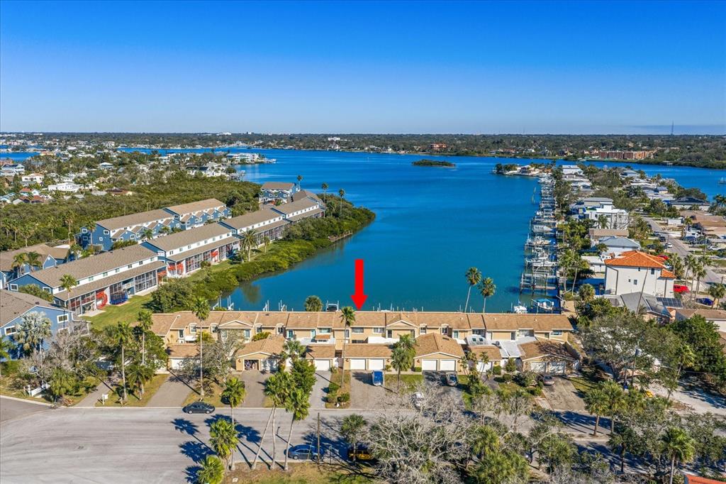 An aerial view shows a row of tan townhouses situated along a waterfront with docks — 829 E GULF BOULEVARD UNIT 107, INDIAN ROCKS BEACH, FL