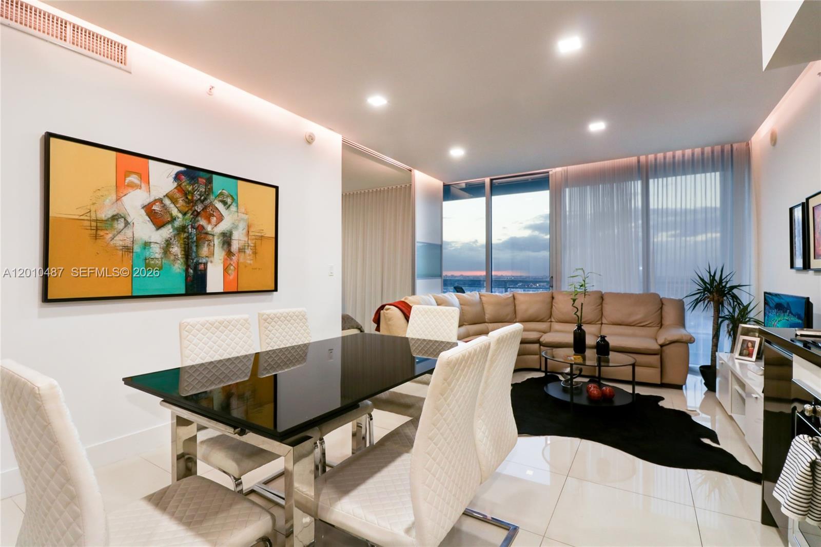 A modern dining and living area features a black table, white chairs, and a sectional sofa — 92 SW 3rd St # 2808, Miami FL 33130, MIAMI, FL