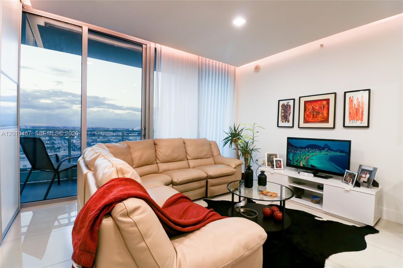 A living room features a beige sectional sofa, a glass coffee table, and a balcony view — 92 SW 3rd St # 2808, Miami FL 33130, MIAMI, FL