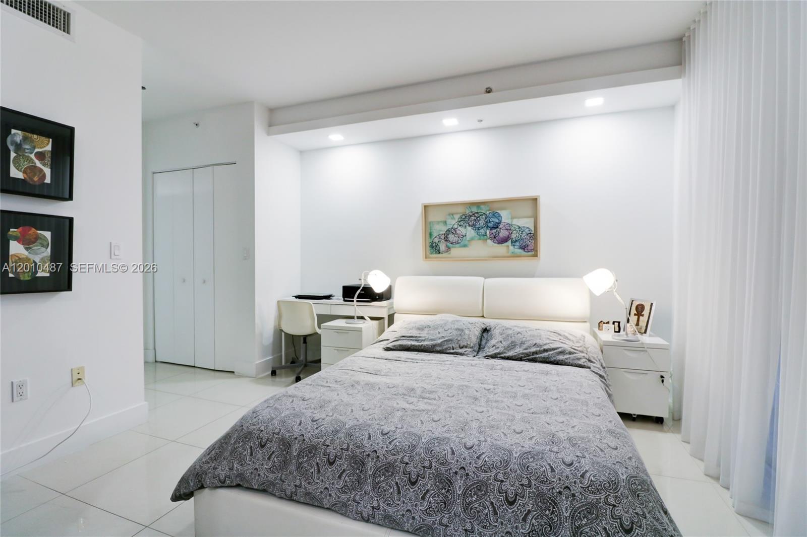 A bedroom features a bed, desk, white tile flooring, and white walls — 92 SW 3rd St # 2808, Miami FL 33130, MIAMI, FL