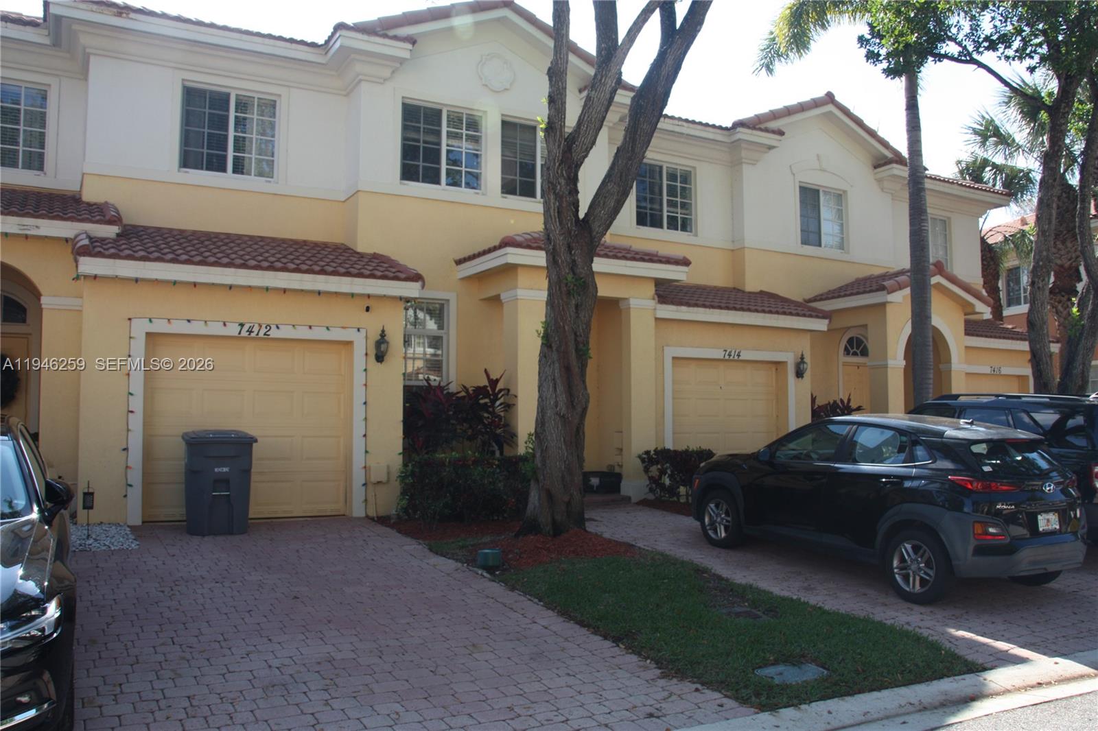 A row of two-story townhouses with yellow stucco facades, tiled roofs, and attached garages — 7414 E Briella Dr, Boynton Beach FL 33437, BOYNTON BEACH, FL