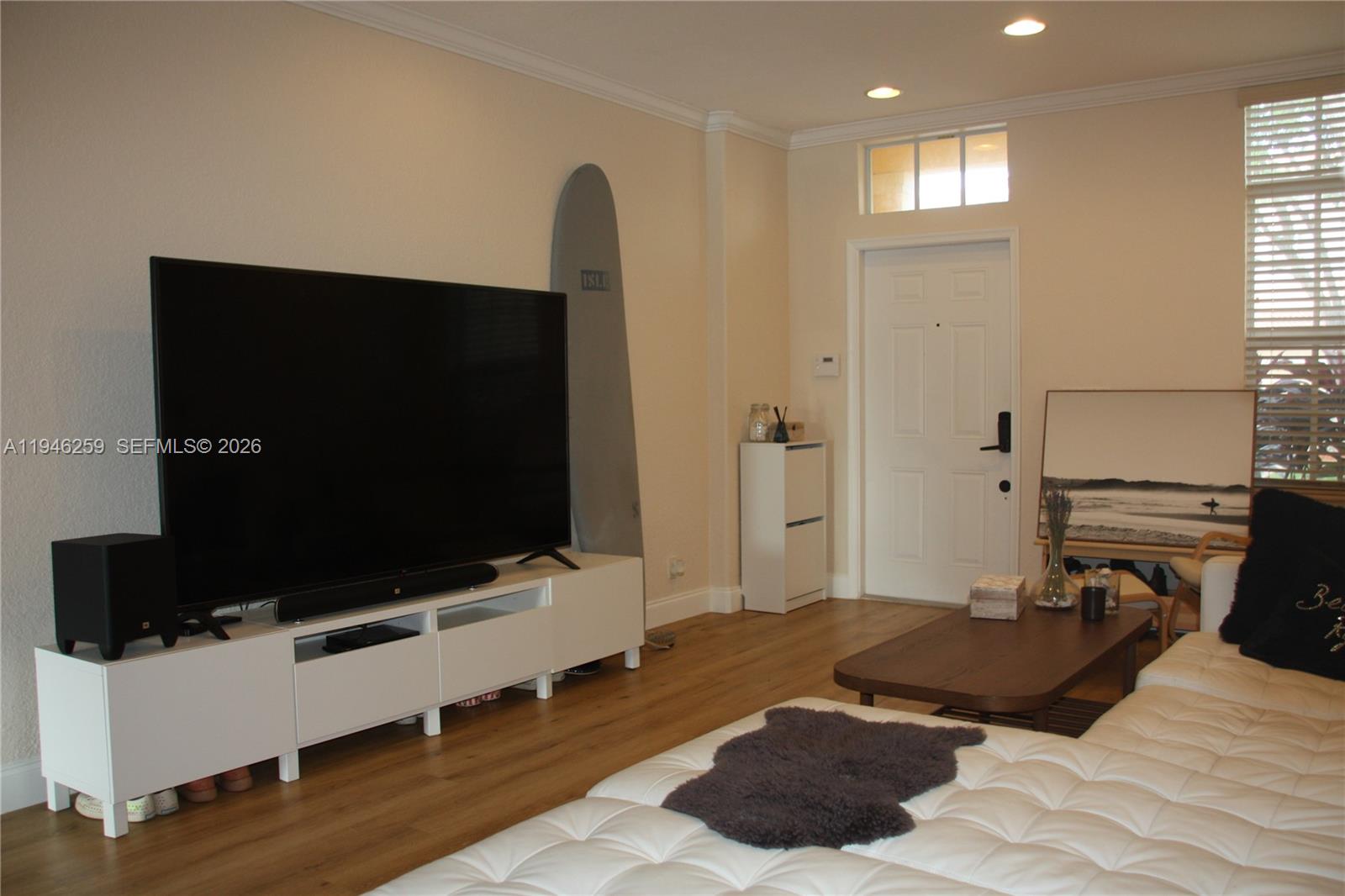 A living room features a large television on a white stand, a surfboard, and a sofa — 7414 E Briella Dr, Boynton Beach FL 33437, BOYNTON BEACH, FL
