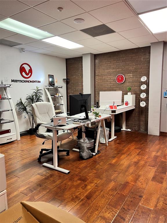 An office space features a desk, a white chair, and a brick accent wall — 377 MAITLAND AVENUE UNIT 1010, ALTAMONTE SPRINGS, FL