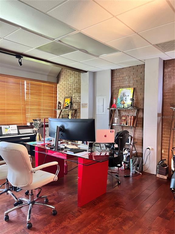 A home office features a red glass desk, a white chair, and brick accent walls — 377 MAITLAND AVENUE UNIT 1010, ALTAMONTE SPRINGS, FL