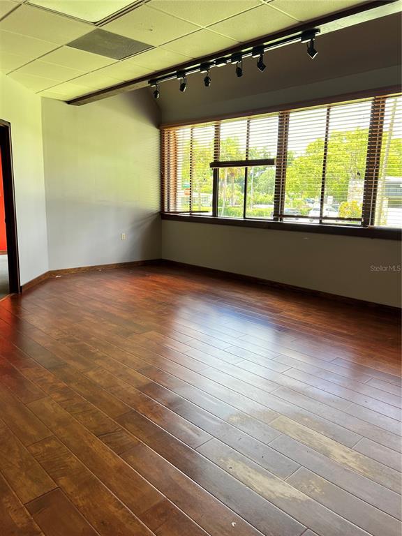 An empty room features wood-look flooring, a track lighting system, and large windows with blinds — 377 MAITLAND AVENUE UNIT 1010, ALTAMONTE SPRINGS, FL