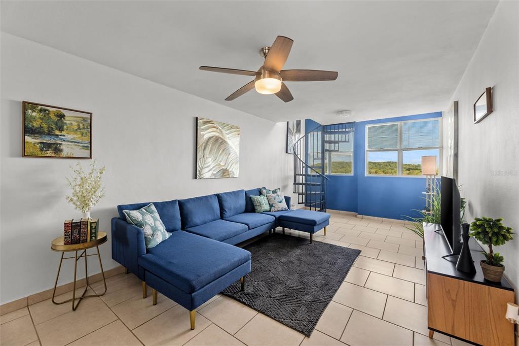 A living room features a blue sectional sofa, a spiral staircase, and tile flooring — Jurel #500 ST. COND. VEREDAS DEL MAR APT 3-307, VEGA BAJA, PR