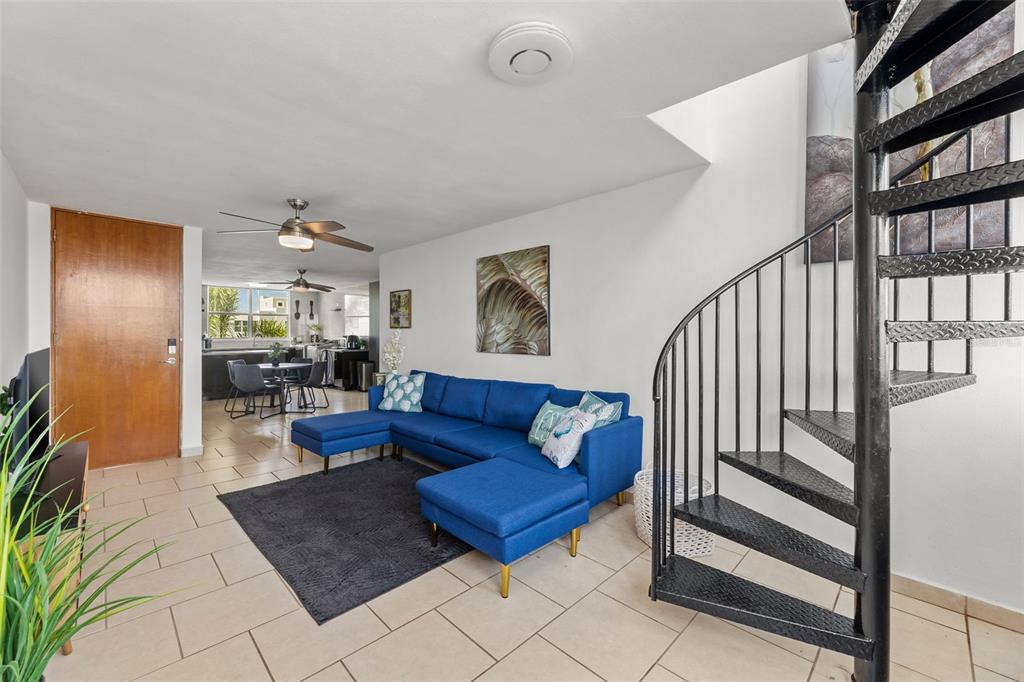A living room features a blue sectional sofa, a spiral staircase, and tile flooring — Jurel #500 ST. COND. VEREDAS DEL MAR APT 3-307, VEGA BAJA, PR