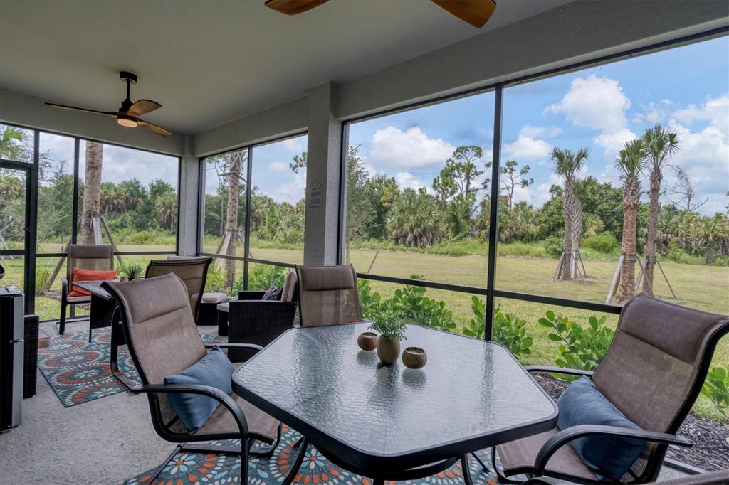A screened-in patio features a dining set, ceiling fans, and views of a grassy field — 14149 POPPY FIELD LOOP UNIT 6011, PUNTA GORDA, FL