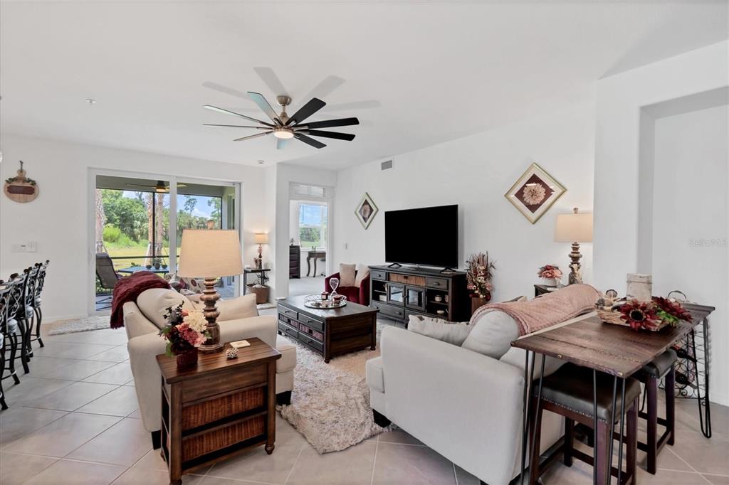 A living room with white walls, a ceiling fan, tile floors, and a sliding glass door — 14149 POPPY FIELD LOOP UNIT 6011, PUNTA GORDA, FL