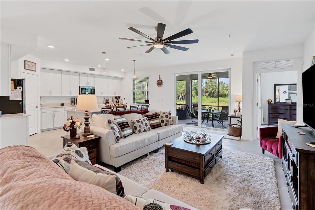 An open-concept living room features a white sofa, a wooden coffee table, and a kitchen — 14149 POPPY FIELD LOOP UNIT 6011, PUNTA GORDA, FL