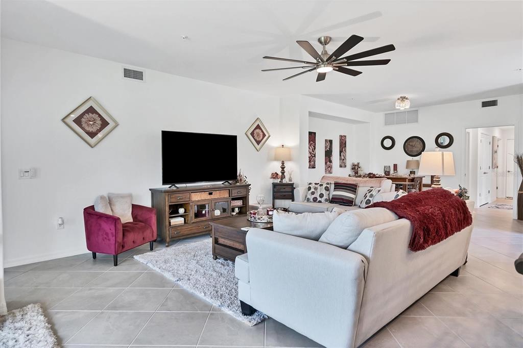 A bright living room features a large sectional sofa, a television console, and tile flooring — 14149 POPPY FIELD LOOP UNIT 6011, PUNTA GORDA, FL