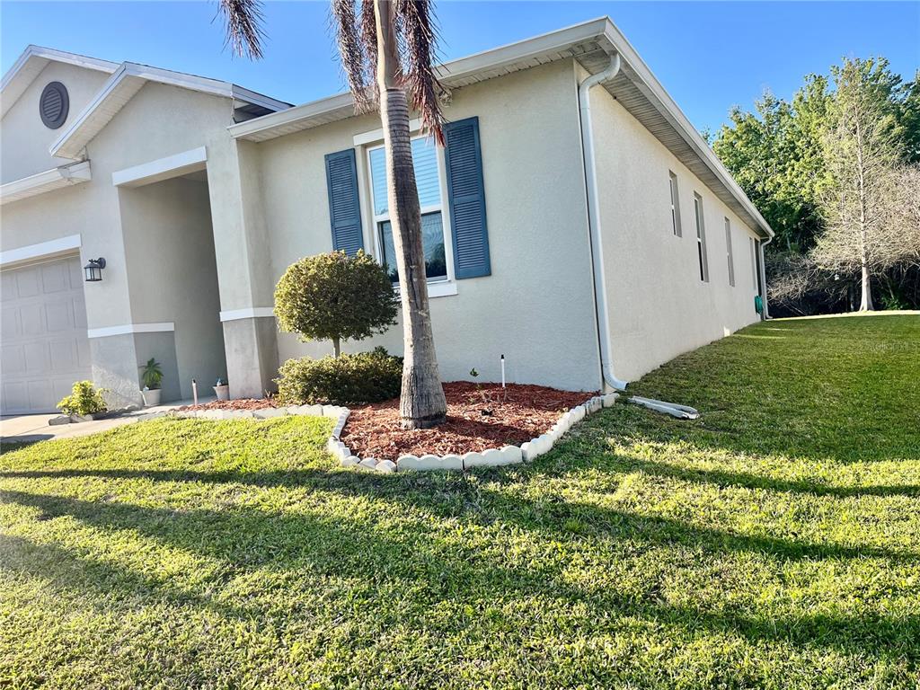 A beige house exterior features a palm tree, a small garden bed, and blue shutters — 2860 BOATING BOULEVARD, KISSIMMEE, FL