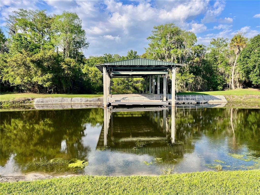A covered boat dock sits on a calm pond surrounded by trees and grassy banks — 2860 BOATING BOULEVARD, KISSIMMEE, FL