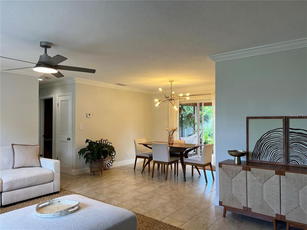 A living and dining area features tile floors, a ceiling fan, and a modern chandelier — 3748 MANATEE DRIVE SE, ST PETERSBURG, FL