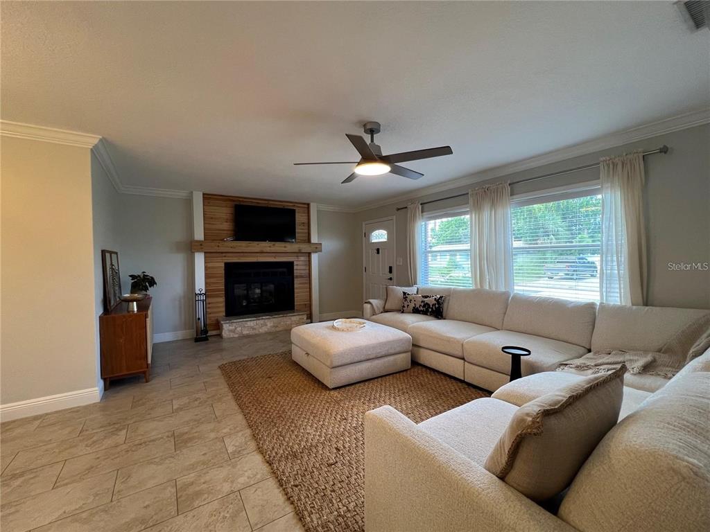 A living room features a fireplace with wood paneling, a sectional sofa, and tile flooring — 3748 MANATEE DRIVE SE, ST PETERSBURG, FL