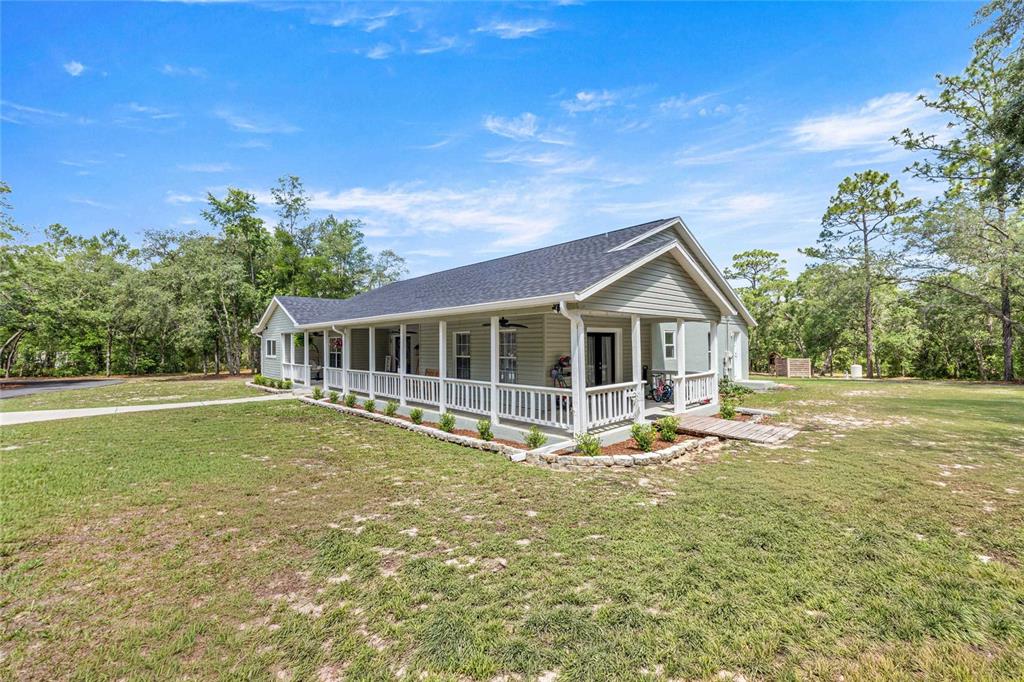 A light green house with a long covered porch sits on a grassy lot — 2301 E MARY LUE STREET, INVERNESS, FL