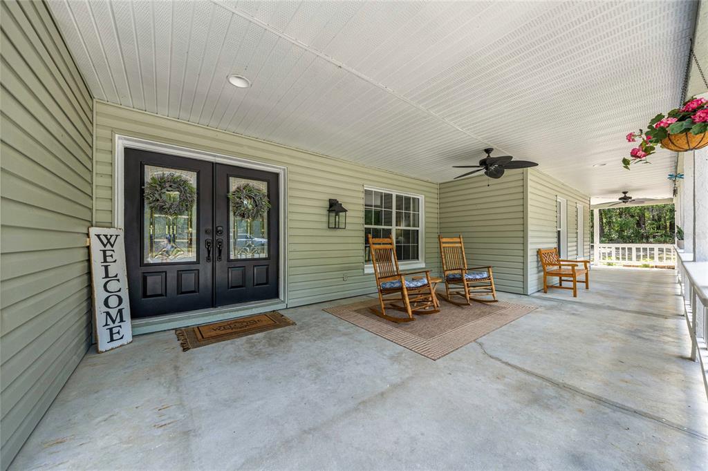A covered porch features light green siding, double front doors, and several wooden rocking chairs — 2301 E MARY LUE STREET, INVERNESS, FL