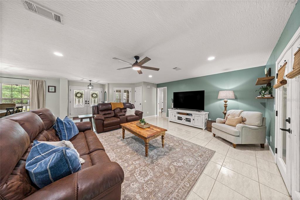 A living room features brown leather sofas, a wooden coffee table, and a television console — 2301 E MARY LUE STREET, INVERNESS, FL