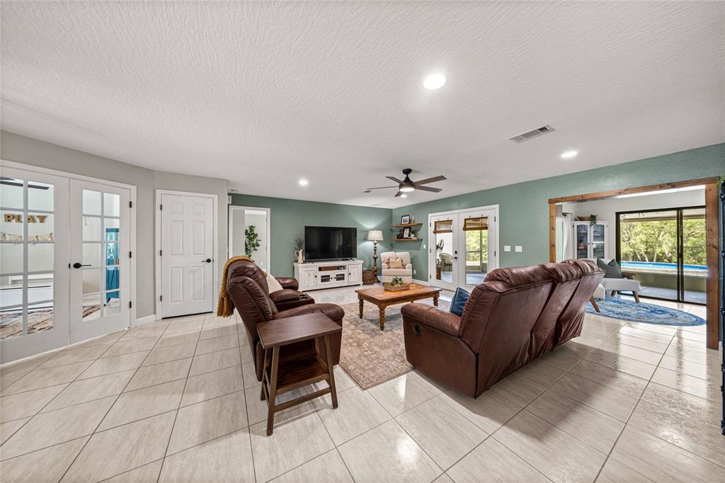 A living room features tile floors, brown leather furniture, and a view of a pool — 2301 E MARY LUE STREET, INVERNESS, FL