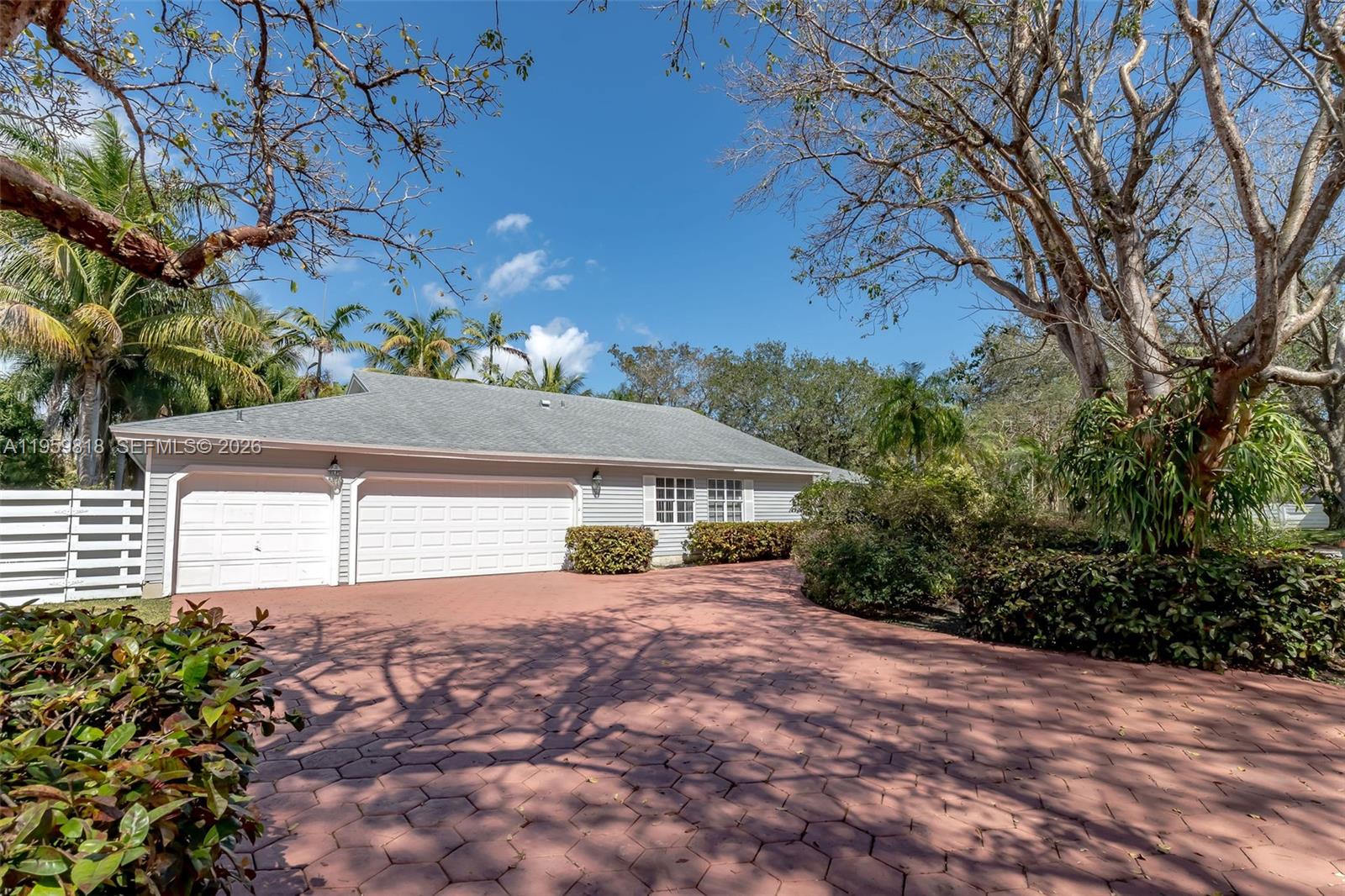 A swimming pool features a stone waterfall, a metal ladder, and surrounding palm trees — 15005 SW 148th St, Miami FL 33196, MIAMI, FL