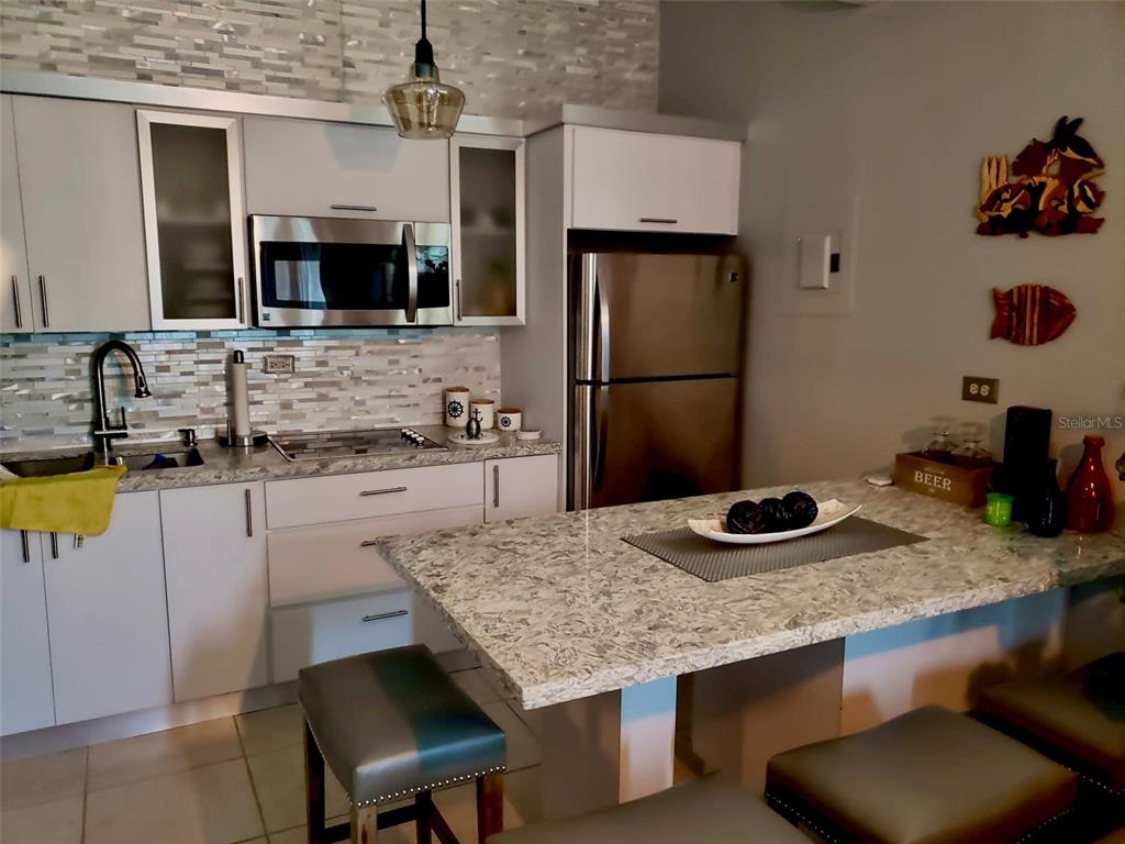 A kitchen features light-colored cabinets, granite countertops, stainless steel appliances, and a breakfast bar — Carr. PR 307 km 8.5 BOQUERÓN BAY SIDE INC APT #23, CABO ROJO, PR