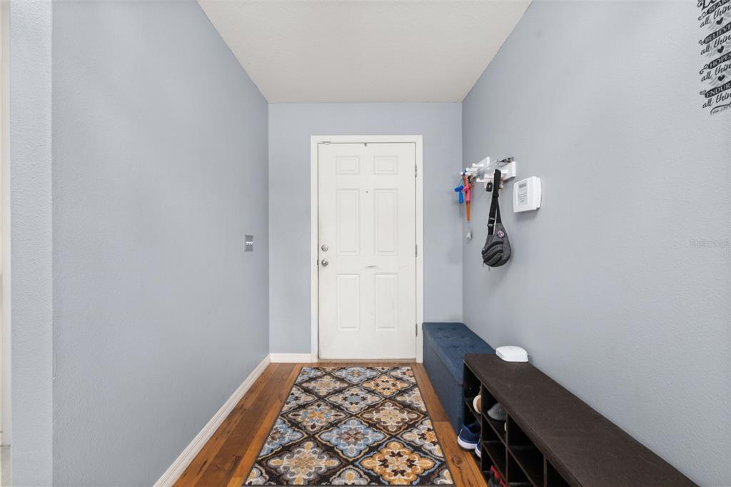 An entryway features light blue walls, a patterned rug, a shoe rack, and a bench — 1321 WOODLARK DRIVE, HAINES CITY, FL