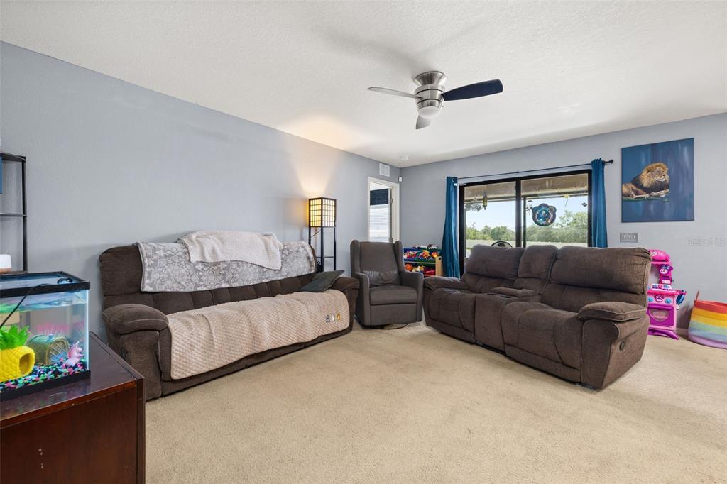 A living room features two brown sofas, a recliner, a fish tank, and a ceiling fan — 1321 WOODLARK DRIVE, HAINES CITY, FL