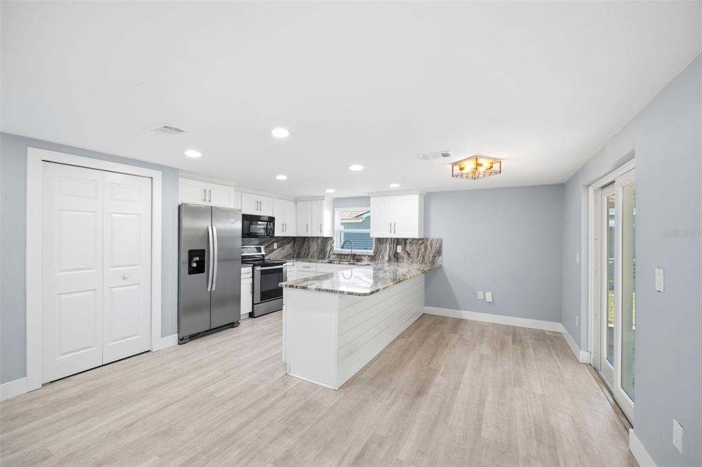 A kitchen features white cabinets, granite countertops, stainless steel appliances, and light wood-look flooring — 12824 1ST ISLE, HUDSON, FL