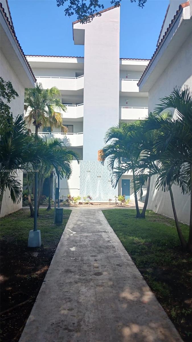 A concrete walkway leads between two residential buildings toward a blue tiled accent wall — 8335 SW 152nd Ave # 310, Miami FL 33193, MIAMI, FL