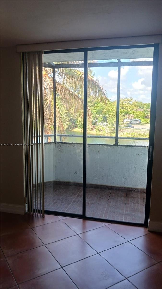 A room with tile flooring features a sliding glass door leading to a screened balcony — 8335 SW 152nd Ave # 310, Miami FL 33193, MIAMI, FL