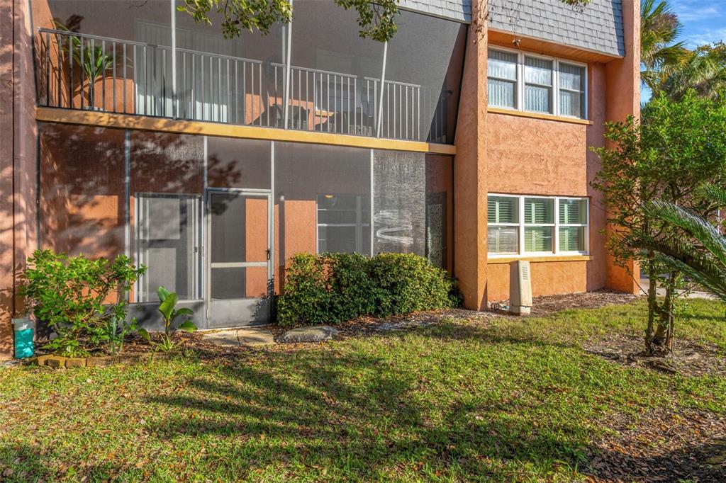 A two-story building with a screened-in ground floor patio and an upper-level balcony — 4805 ALT 19 UNIT 311, PALM HARBOR, FL