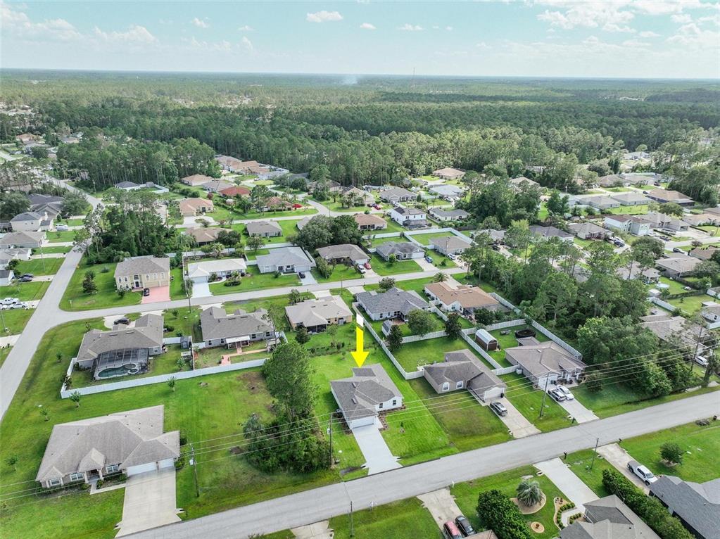 An aerial view shows a suburban neighborhood with single-family homes, green lawns, and paved streets — 134 RED MILL DRIVE, PALM COAST, FL