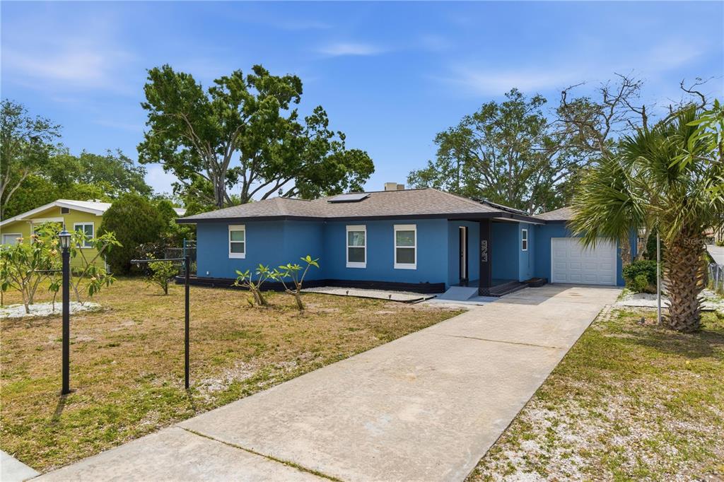 A blue single-story house with a concrete driveway, a garage, and a large front yard — 923 1ST AVENUE NW, LARGO, FL