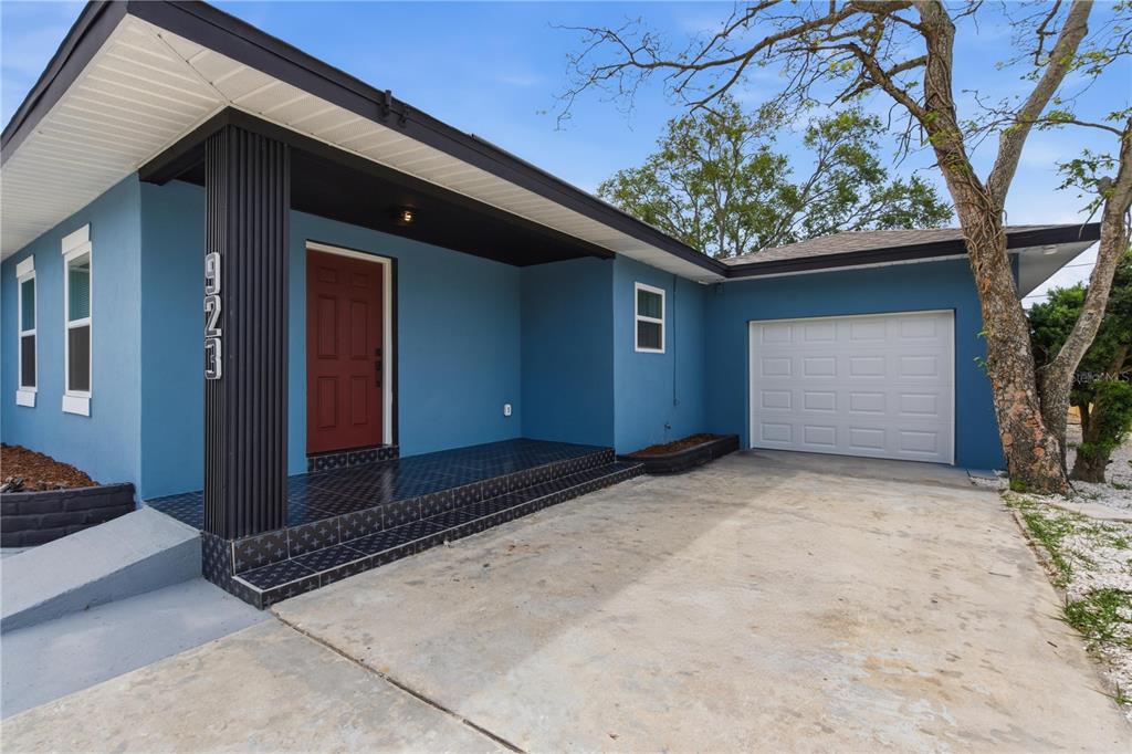 A blue house exterior features a red front door, a tiled porch, and a garage — 923 1ST AVENUE NW, LARGO, FL
