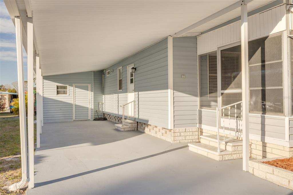 A covered carport area with light blue siding, concrete flooring, and two sets of stairs — 29250 US HIGHWAY 19 N UNIT 537, CLEARWATER, FL